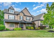 Inviting two-story brick home with lush landscaping and covered front porch at 15637 Guthrie Dr, Huntersville, NC 28078