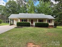 Charming single-story home featuring red shutters, a carport, and lush green landscaping at 1833 Bardell St, Lancaster, SC 29720