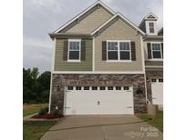 Two-story townhome featuring a white garage door, stone facade, and complementary green and beige siding at 3207 Lilac Grove Dr, Charlotte, NC 28269