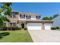 Charming brick and siding two-story home featuring a spacious three-car garage and well-manicured lawn at 4321 Tucker Chase Dr, Midland, NC 28107