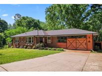 Charming brick home featuring a well-manicured lawn, lovely landscaping, and a uniquely designed garage door at 851 Gist Rd, Rock Hill, SC 29732