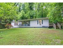 Charming ranch home featuring a cozy porch, a small set of stairs, surrounded by lush greenery and a well-maintained lawn at 857 Hills Rd, Belmont, NC 28012