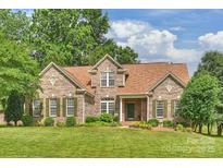 Charming brick home featuring a manicured lawn, complemented by lush greenery and mature trees at 1117 Yarrow St, Matthews, NC 28104