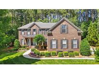 Charming brick two-story home featuring manicured landscaping and a welcoming front porch at 129 Willow Tree Ln, Mount Holly, NC 28120