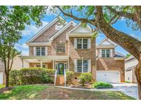 Charming brick home with lush landscaping, white shutters, and a welcoming front porch at 14426 Harvington Dr, Huntersville, NC 28078