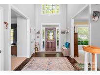 Inviting foyer with dark hardwood floors, decorative rug, front door with transom window, and high ceilings at 16028 Hallaton Dr, Huntersville, NC 28078