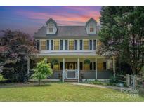 Charming two-story home with a inviting front porch, beautiful landscaping, and traditional design at 1687 Windy Hill Ln, Great Falls, SC 29055