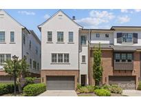 Modern townhome exterior featuring a gray garage door, a combination of stucco and brick, and a well-maintained lawn at 4030 City Homes Pl, Charlotte, NC 28209