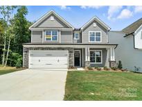 Two-story home featuring gray siding, a two-car garage, and a well-manicured lawn at 5103 Heathland Dr # 50, Charlotte, NC 28215