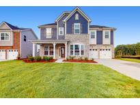 Charming two-story home boasts stone accents, blue siding, well-manicured lawn, and attached two car garage at 8286 Ashvale Nw St, Concord, NC 28027