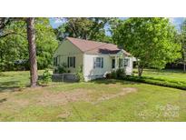 Charming single-story home with yellow siding, brown roof, and lush surrounding trees, nestled in a serene neighborhood at 1302 N Ellis St, Salisbury, NC 28144