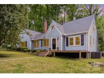 Charming light-blue home featuring a covered porch, manicured lawn, and mature trees providing a serene backdrop at 200 Cleveland Ave, Shelby, NC 28150