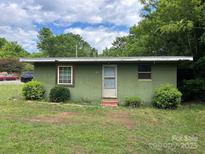 Modest single-story house with green exterior, simple landscaping, and mature trees in a yard at 2703 E Greenbriar Rd, Statesville, NC 28625