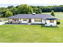 Charming white brick home with a black roof and shutters set on a large lawn at 5710 Lander Benton Rd, Unionville, NC 28110