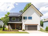 Striking two-story home with white and gray siding, solar panels, and a modern garage door at 5777 Stephanie St, Charlotte, NC 28212