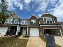 New townhomes with brick and siding exteriors, showcasing modern design and attached garages under a cloudy sky at 6256 Culbert St # 187, Harrisburg, NC 28075