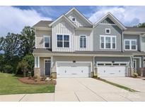 View of a charming townhome with a manicured lawn, two-car garage, and neutral color scheme at 8221 Houser St, Cornelius, NC 28031