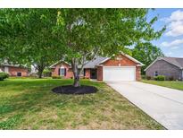 Charming brick home with a well-manicured lawn and a mature shade tree in the front yard at 8309 Emily Dr, Harrisburg, NC 28075