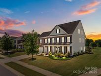 Charming brick two-story home with a welcoming front porch and meticulously landscaped front yard at 9871 Travertine Trl, Davidson, NC 28036
