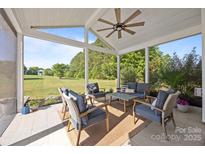 Covered porch features plush furniture and ceiling fan overlooking the manicured lawn at 9871 Travertine Trl, Davidson, NC 28036