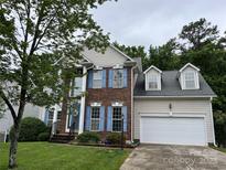 Charming brick home with blue shutters and a well-manicured lawn and two car garage at 12317 Panthersville Dr, Charlotte, NC 28269