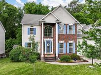 Charming two-story home with brick accents, a well-manicured lawn, and inviting blue shutters at 12317 Panthersville Dr, Charlotte, NC 28269