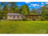 Charming single story home featuring covered porch, metal roof, manicured lawn, and mature trees at 3755 River Rd, Richfield, NC 28137