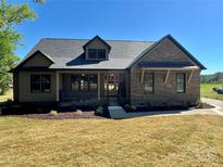 Charming single-story brick home with a covered front porch and professionally landscaped yard at 603 Turnberry Ct, Albemarle, NC 28001