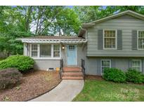 Charming home featuring a light blue front door, a landscaped yard, and a gray painted brick front at 6609 Pleasant Dr, Charlotte, NC 28211