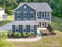 Charming two-story home with blue siding, shutters, well-maintained landscaping, and a walkway to the front door at 8268 Breton Way, Harrisburg, NC 28075