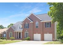 Charming two-story brick home with a well-maintained lawn, attached two-car garage, and classic architectural details at 1465 Porters Ct, Concord, NC 28025