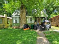Charming green home with a stone chimney and inviting front yard, perfect for relaxing or entertaining at 2204 Rozzelles Ferry Rd, Charlotte, NC 28208