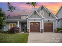 Charming home with a two-car garage, manicured lawn, and inviting curb appeal against a colorful sunset sky at 4016 Spring Cove Way, Belmont, NC 28012