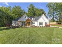 Beautiful white farmhouse with a manicured lawn and inviting front porch at 518 Maynard Farm Ln, Stanley, NC 28164