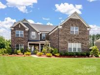 Stunning two-story brick home featuring a well-manicured lawn and beautiful landscaping at 709 Cavesson Way, Monroe, NC 28110