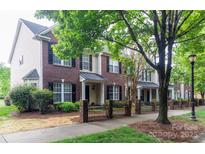 Row of brick townhomes featuring black shutters and wrought iron fence along a tree lined sidewalk at 9532 Cadman Ct, Cornelius, NC 28031