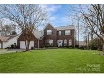 Charming two-story brick home with a well-manicured lawn and a welcoming light blue front door at 104 Steamboat Dr, Mount Holly, NC 28120
