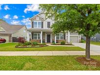 Charming two-story home with a well-manicured lawn, inviting front porch, and attached two-car garage at 10906 Charmont Pl, Huntersville, NC 28078