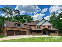 Stunning two-story home featuring a three-car garage, inviting front porch, and lush green lawn at 1140 Fern Hill Rd, Mooresville, NC 28117