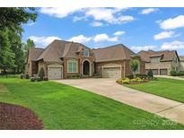 Beautiful brick home featuring a three-car garage, manicured lawn and lush landscaping at 1400 Delaney Dr, Matthews, NC 28104