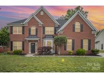 Charming two-story brick home with lush green lawn and meticulously maintained landscaping at sunset at 15037 Taylor Ridge Ln # 25, Charlotte, NC 28273