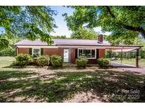 Charming brick home featuring a covered carport, mature trees, and a well-maintained lawn at 175 Triplett Rd, Cleveland, NC 27013