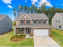 Charming two-story brick home with a well-manicured lawn, two-car garage and beautiful landscaping at 191 Tackle Box Dr, Troutman, NC 28166