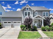 Beautiful gray two-story home featuring a manicured lawn, two-car garage, and charming covered porch at 2025 Masons Bend Dr, Fort Mill, SC 29708