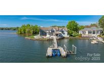 Lakefront home featuring a private dock with boat lifts and lakeside patio with seating areas at 3386 Governors Island Dr, Denver, NC 28037