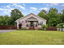 Charming single-Gathering home boasts a well-manicured lawn and cozy, covered front porch with brick steps at 5252 Ramblewoods Ave, Claremont, NC 28610