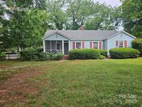 Charming single-story home with light blue siding, red shutters, and a cozy screened front porch at 6407 Market St, Charlotte, NC 28215