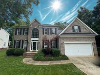 Charming two-story brick home with a well-manicured lawn and attached two-car garage at 7006 Olde Sycamore Dr, Mint Hill, NC 28227