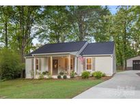 Charming home with a covered front porch, landscaped garden, and a well-maintained green lawn at 7416 Cross Tie Ct, Mint Hill, NC 28227