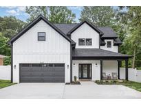 Modern farmhouse exterior featuring black trim, white siding, a two-car garage, and a cozy front porch at 9527 Walkers Ferry Rd, Charlotte, NC 28214